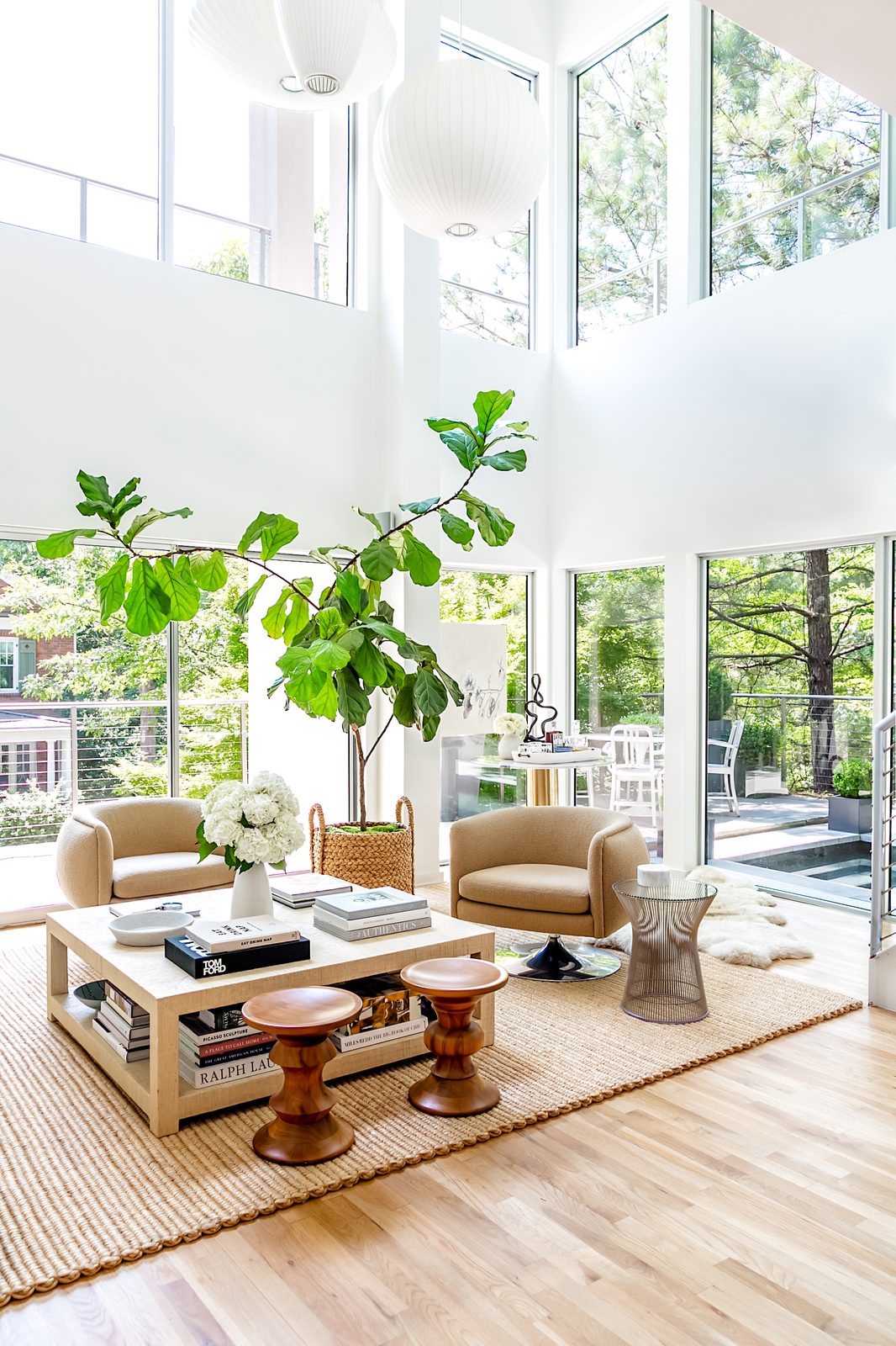 Editorial interior photography of a bright modern living room with double-height windows, fiddle leaf fig tree, and carefully styled coffee table, the kind of hero image that leads a magazine feature