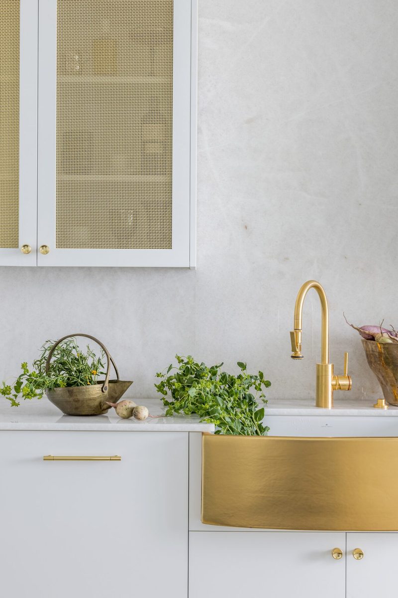 Detail shot of a custom brass apron sink with white cabinetry: an example of the close-up photography that captures material texture and craftsmanship during an interior design shoot