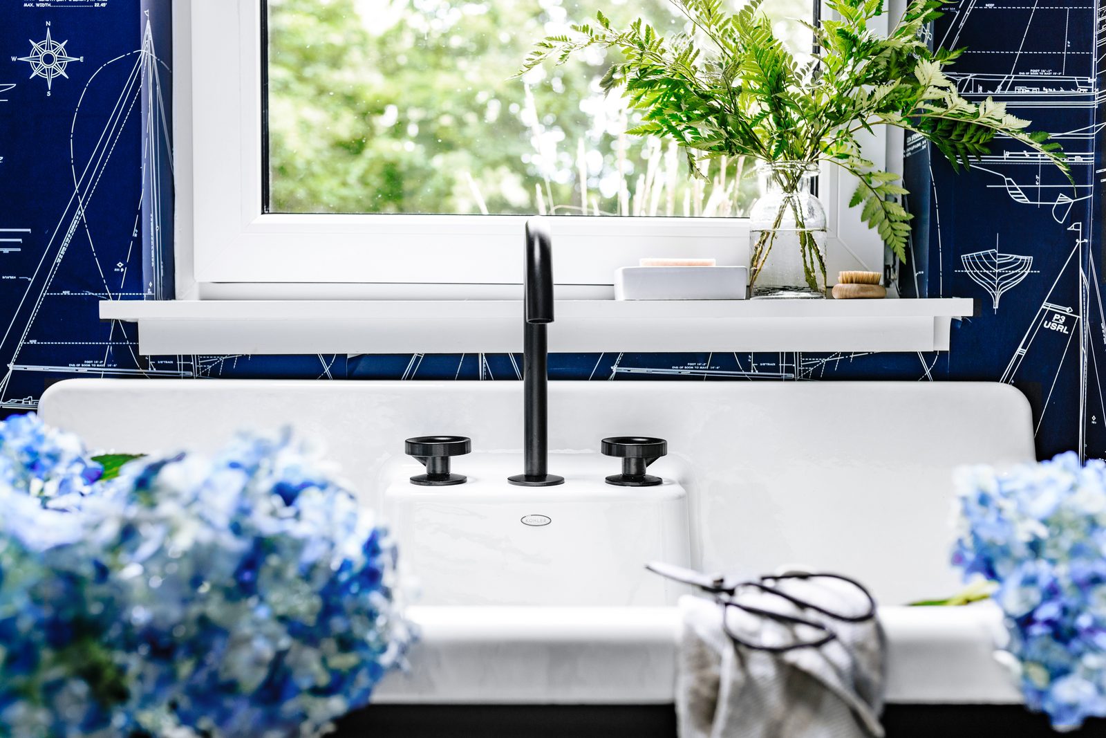 Close-up detail vignette of a powder-room faucet and stone basin, the kind of tight composition that fuels a designer's Instagram rotation and breaks up the rhythm of a project page.