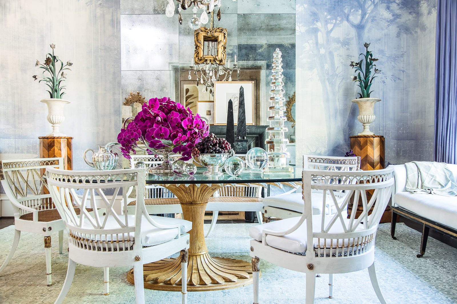 Publication-ready interior design — a showhouse dining room with white rattan chairs, a mirrored table, and fuchsia florals, styled as the hero shot that opens a magazine feature.