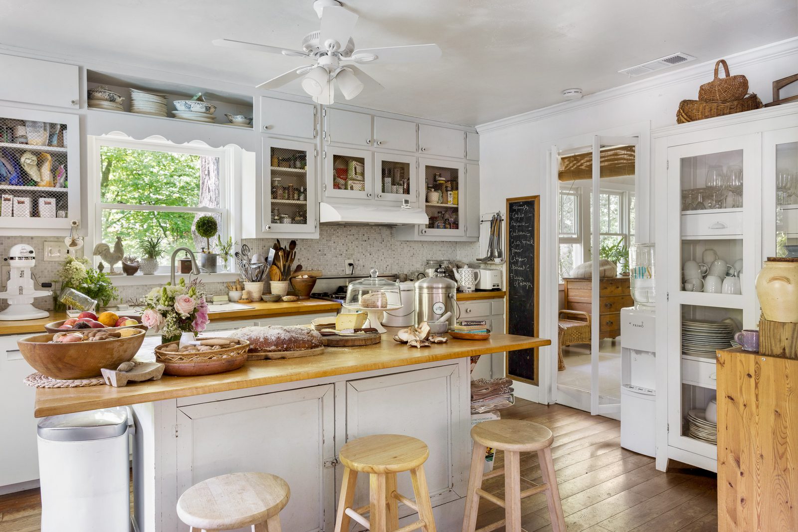 Cottage kitchen with open shelving and layered countertop styling — foreground, mid-ground, and background working together inside one publication-ready frame.