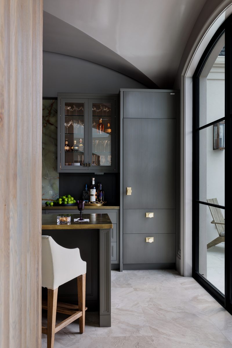 Moody wet bar with an arched window showing bright daylight outside while the interior stays evenly lit: the exact contrast a strobe is used to balance.