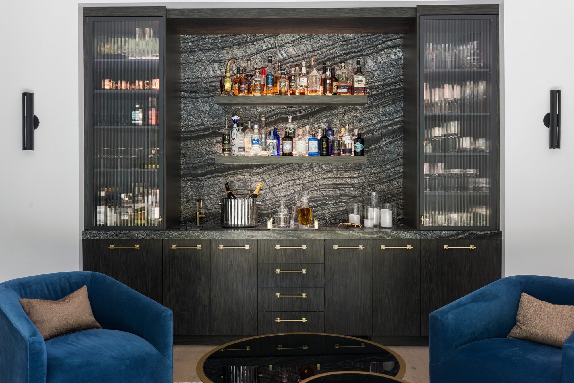Custom built-in bar with dark stone backsplash and glass cabinets